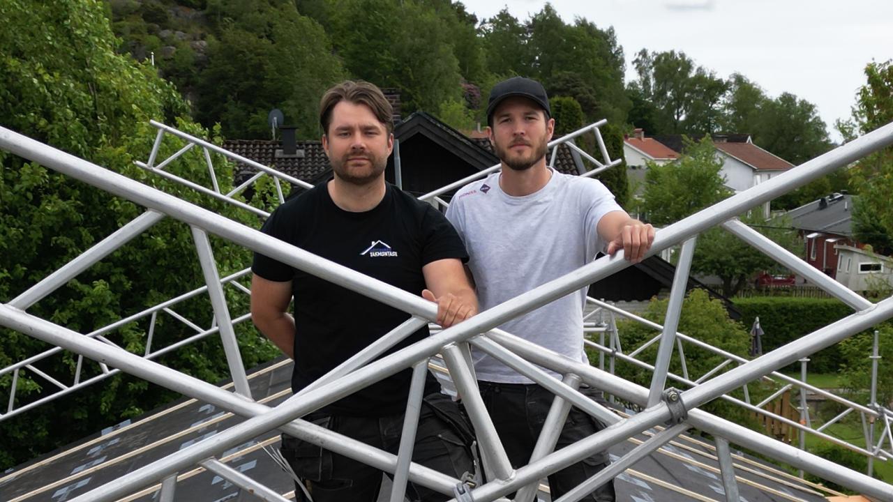 Två män på ett tak med byggnadsställningar