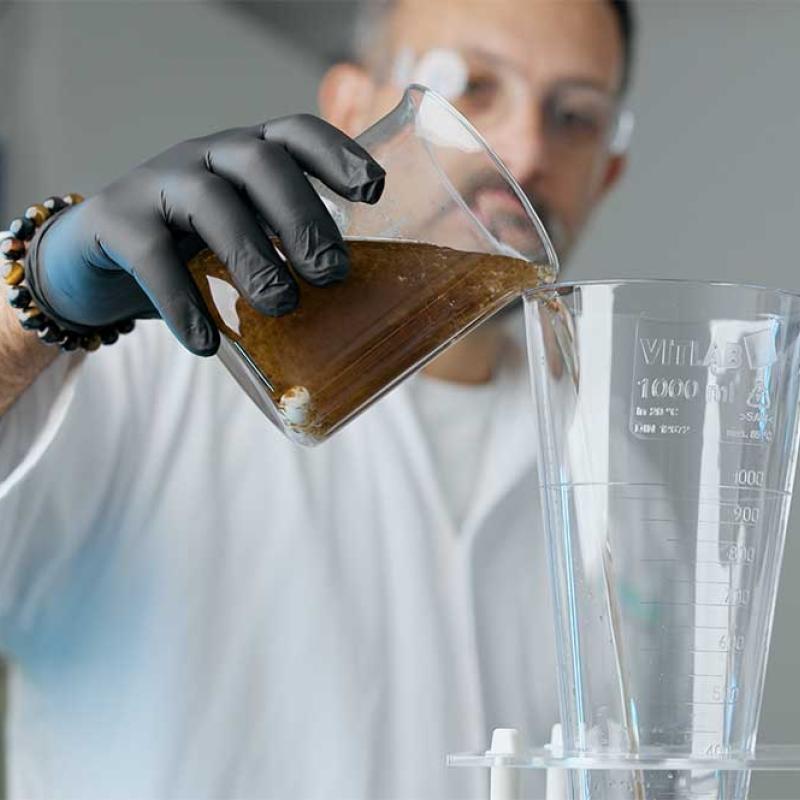 Man häller förorenat vatten i ett glas