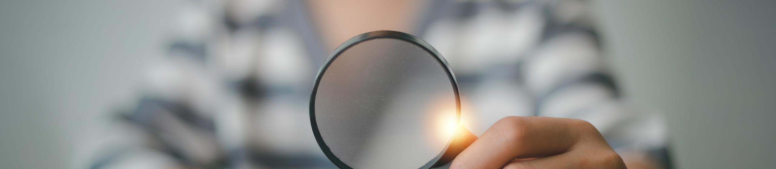 Bild på person som håller ett förstoringsglas