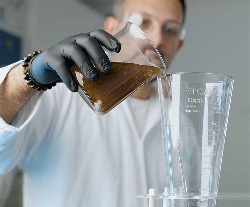 Man häller förorenat vatten i ett glas