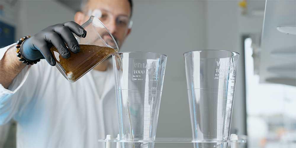 Man häller brunt vatten i ett glas